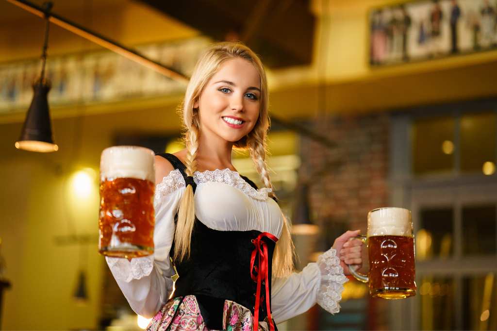 smiling German blonde girl carries beer at the Oktoberfest festival in Mallorca