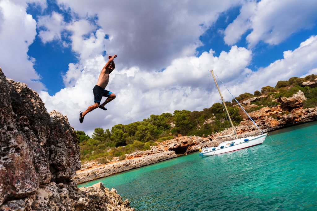 Man Jumping off Cliffs on Sunny Cala Sa Nau, Mallorca