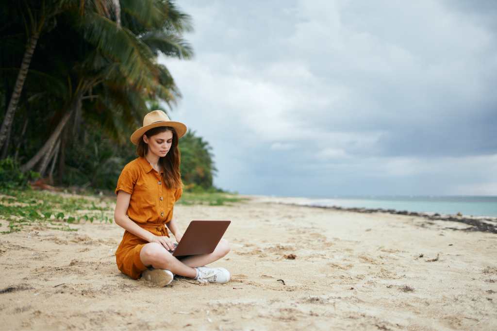 remote work - girl working at a laptop on the seashore