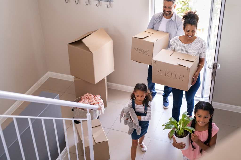 A family moves into a ready-made house, parents and children bring boxes into the new house