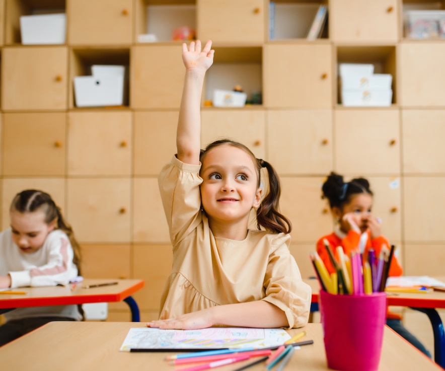 girl raising her hand in a classroom