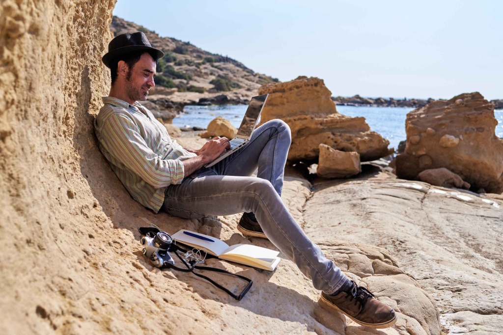 man working remotely on the beach