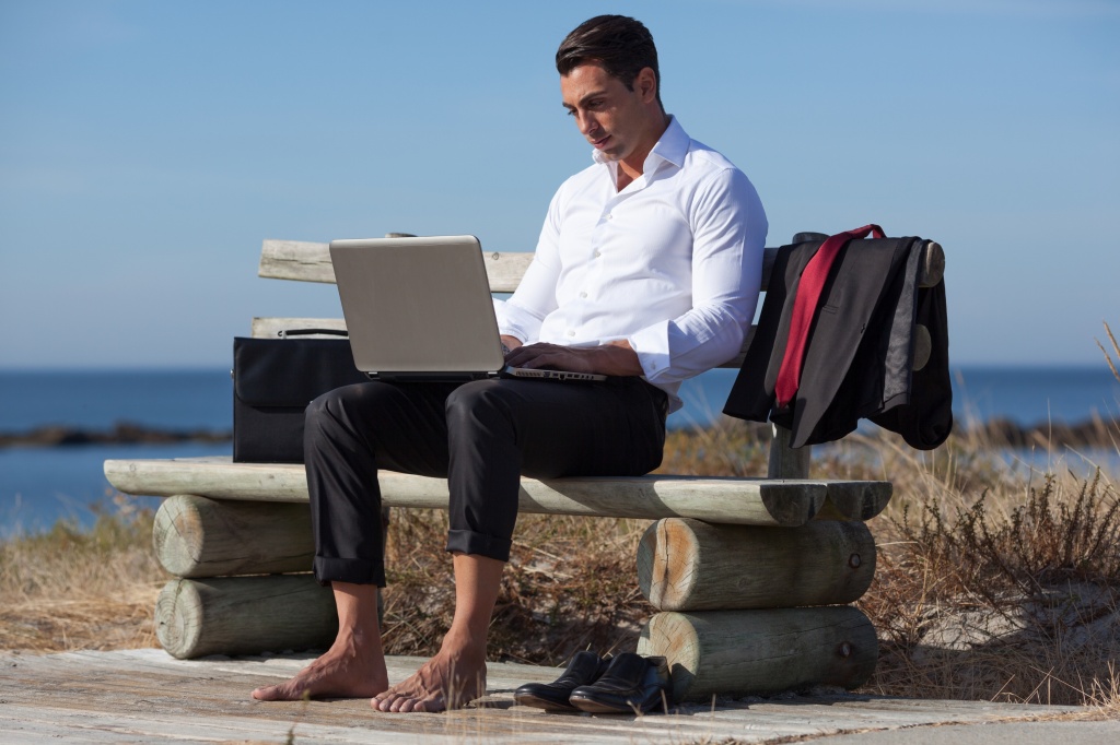 Man working on laptop on the beach